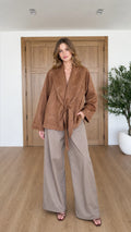 Front full view of woman wearing Camel faux suede tie-front jacket with wide-leg trousers