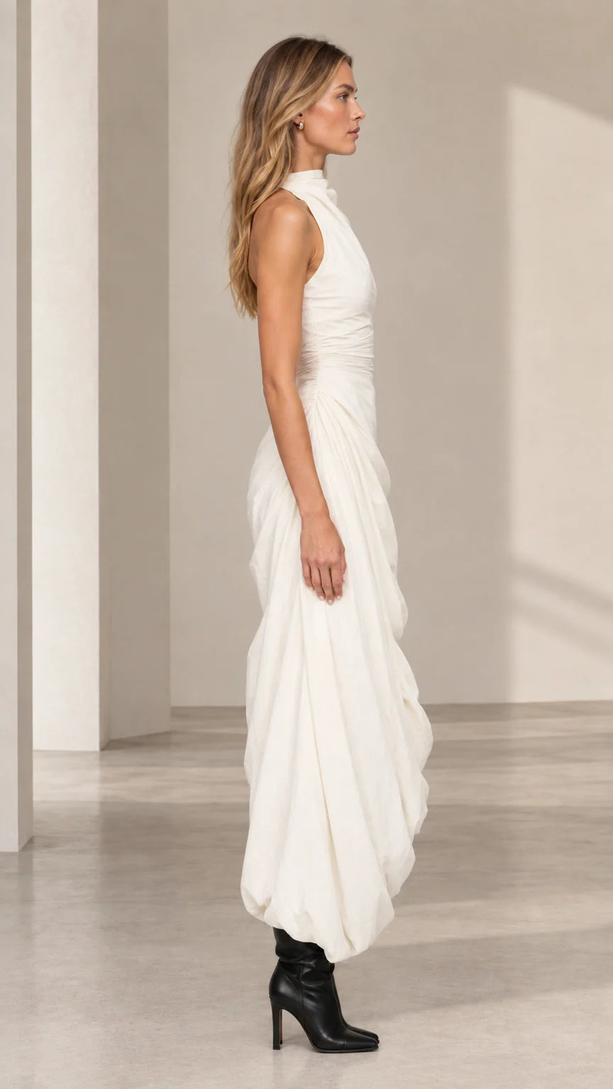 Side profile of model in ivory sleeveless draped maxi dress with bubble hem