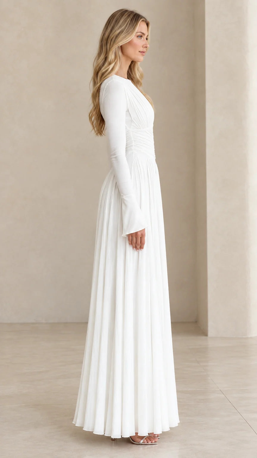 Side profile view of model in white pleated long sleeve formal gown