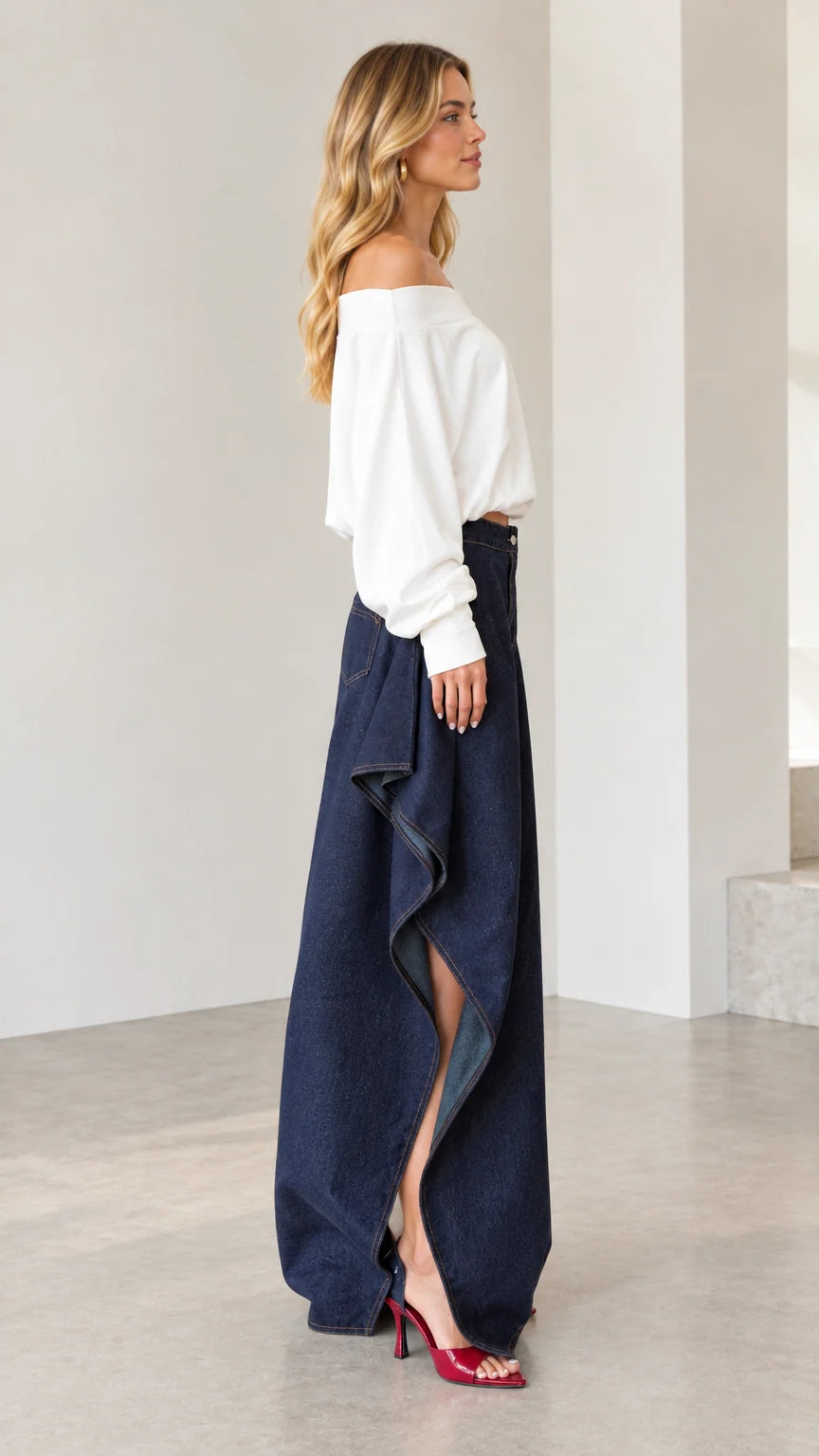 Side profile view showing dramatic cascading drape and side slit on dark blue wide-leg jeans