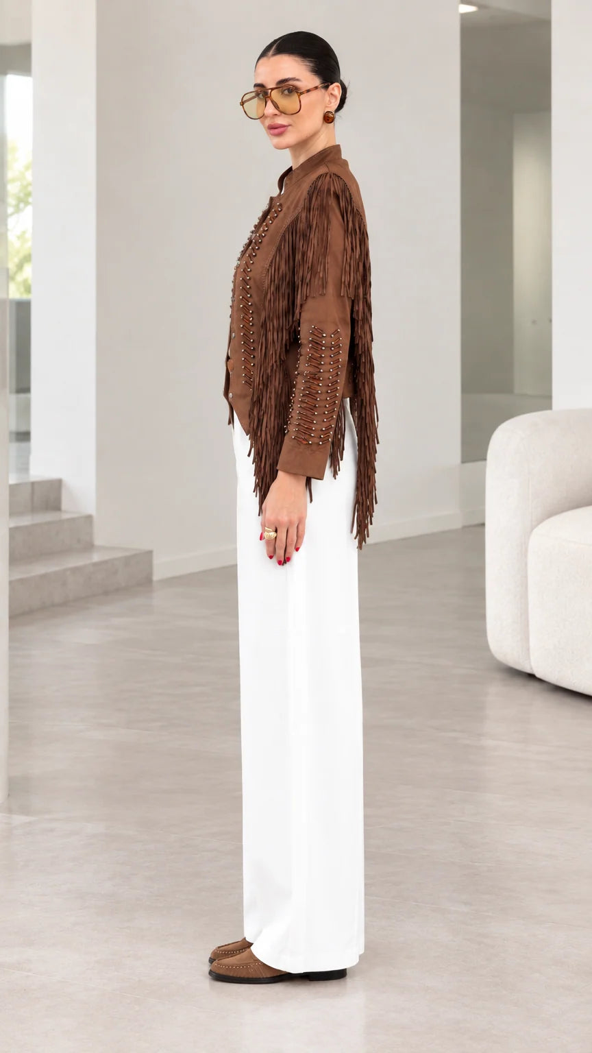 Side profile view of model showcasing sleeve fringe on brown suede jacket