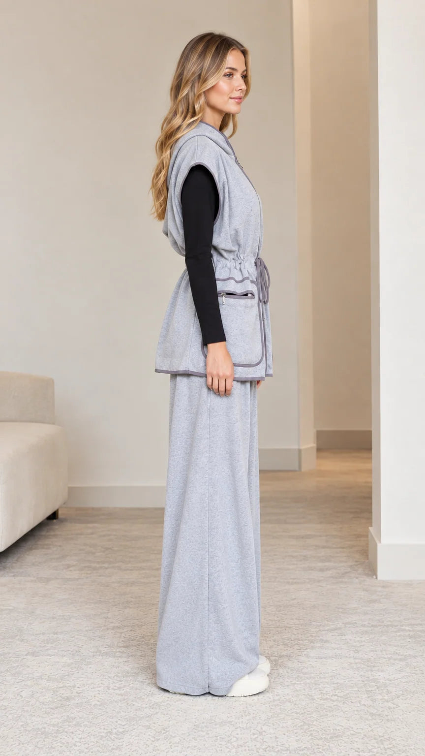 Side profile view of model in heather grey drawstring hooded vest and relaxed trousers
