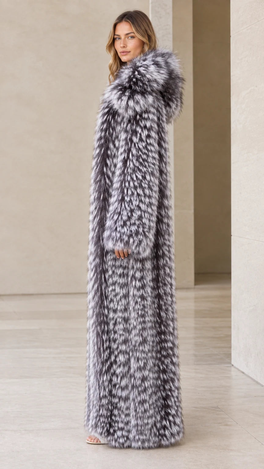 Side profile view of woman wearing long silver grey hooded faux fur coat