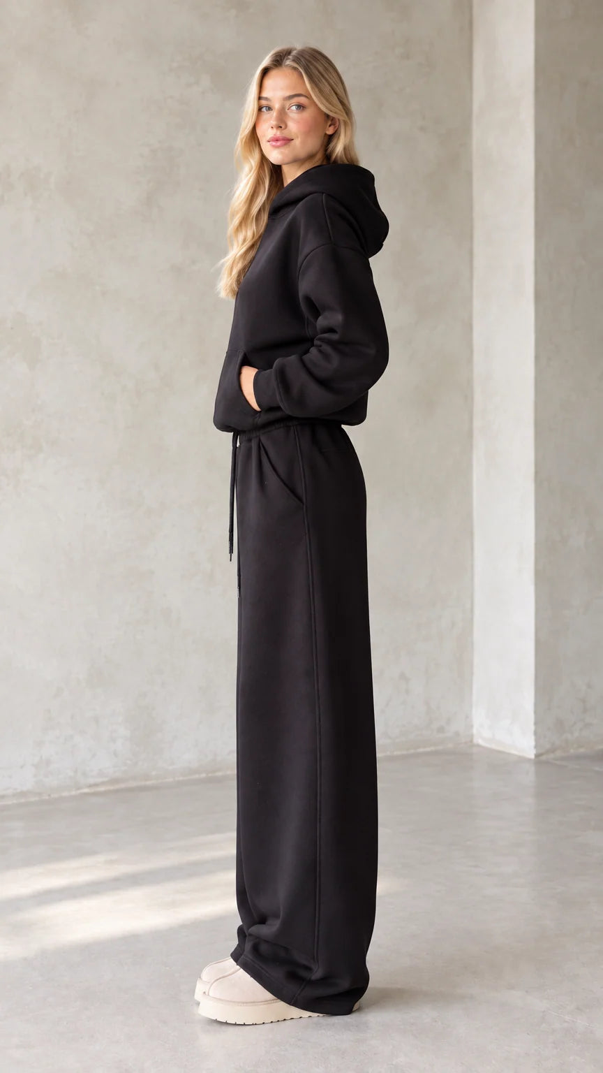 Side profile view of black fleece hoodie and wide leg sweatpants set