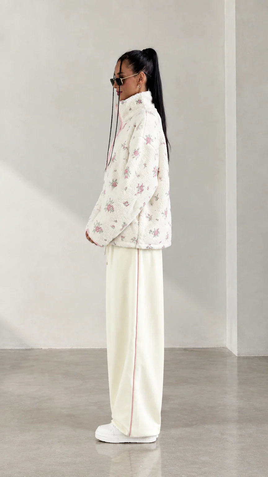 Side profile view of model wearing cream floral half-zip fleece jacket