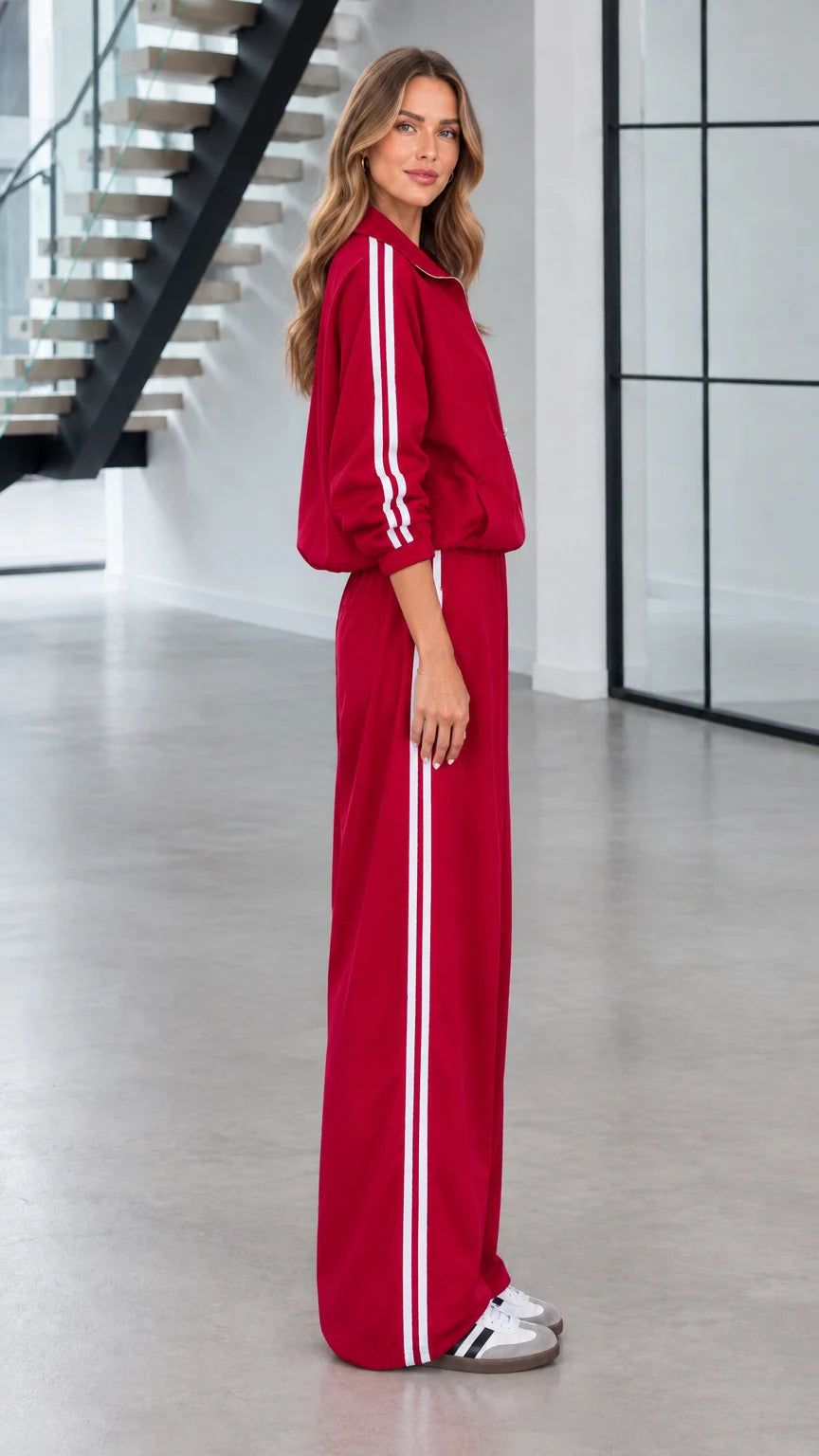 Side profile view of red zip-up jacket and wide-leg striped track pants