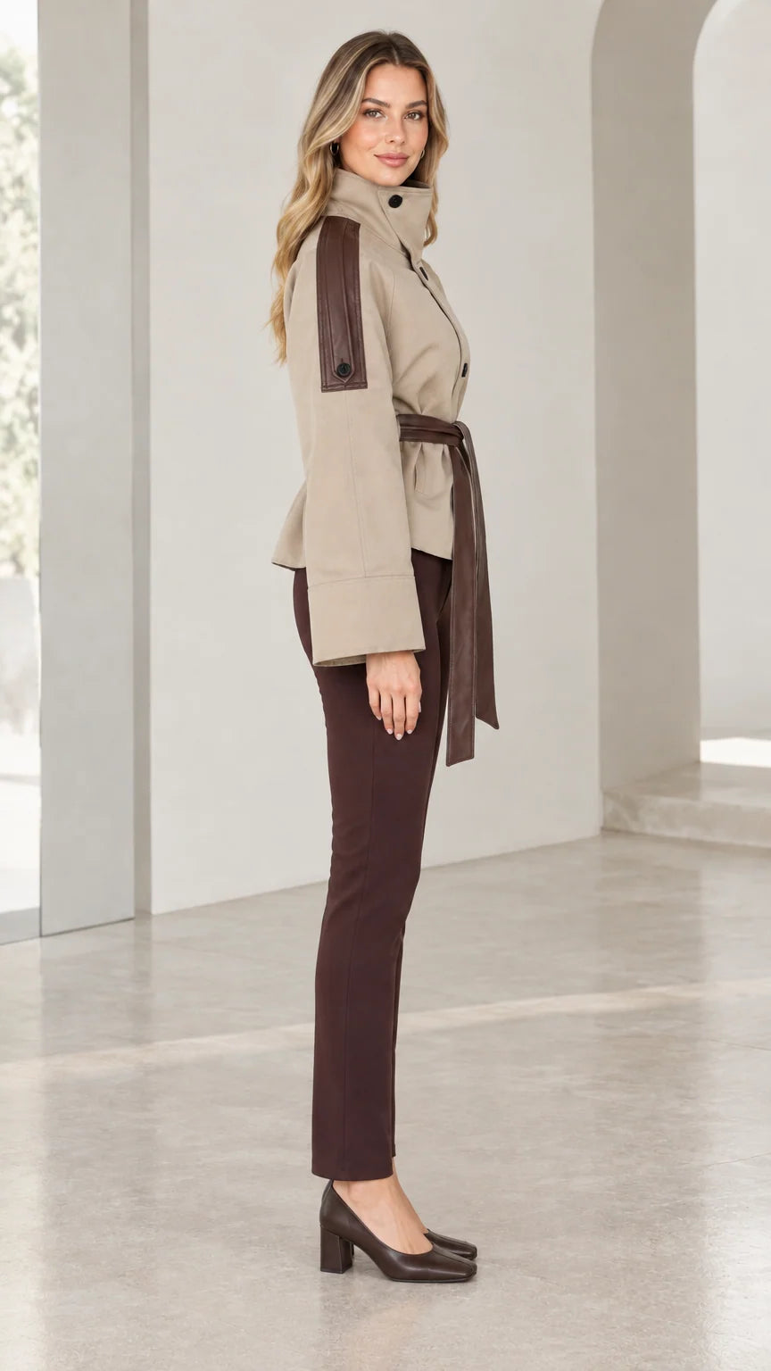 Side profile of model wearing beige short belted jacket with contrast shoulder trim