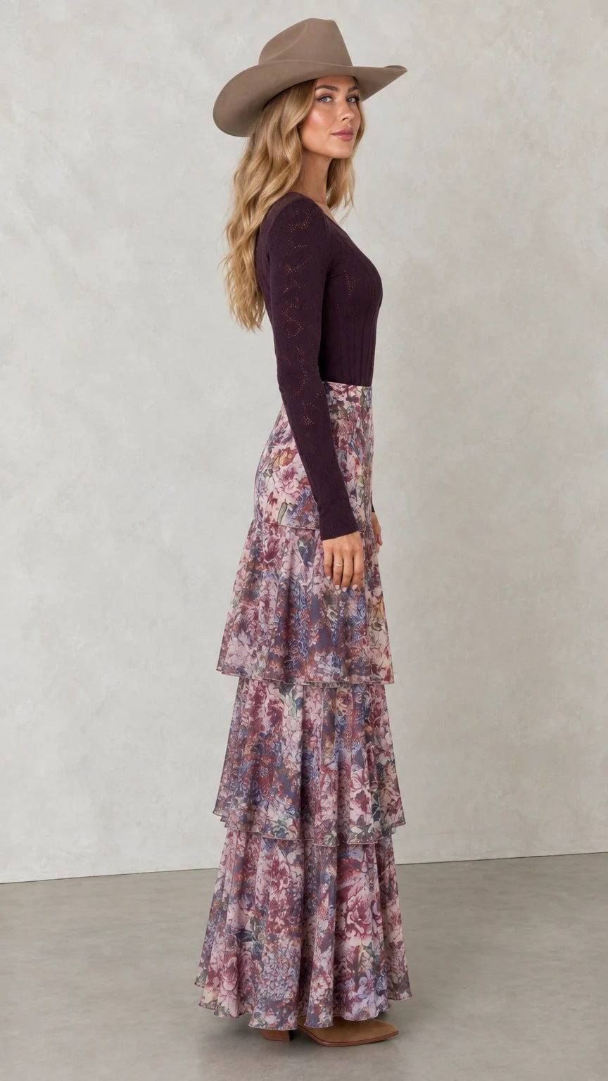 Side profile view of woman wearing flowy tiered floral maxi skirt with boots