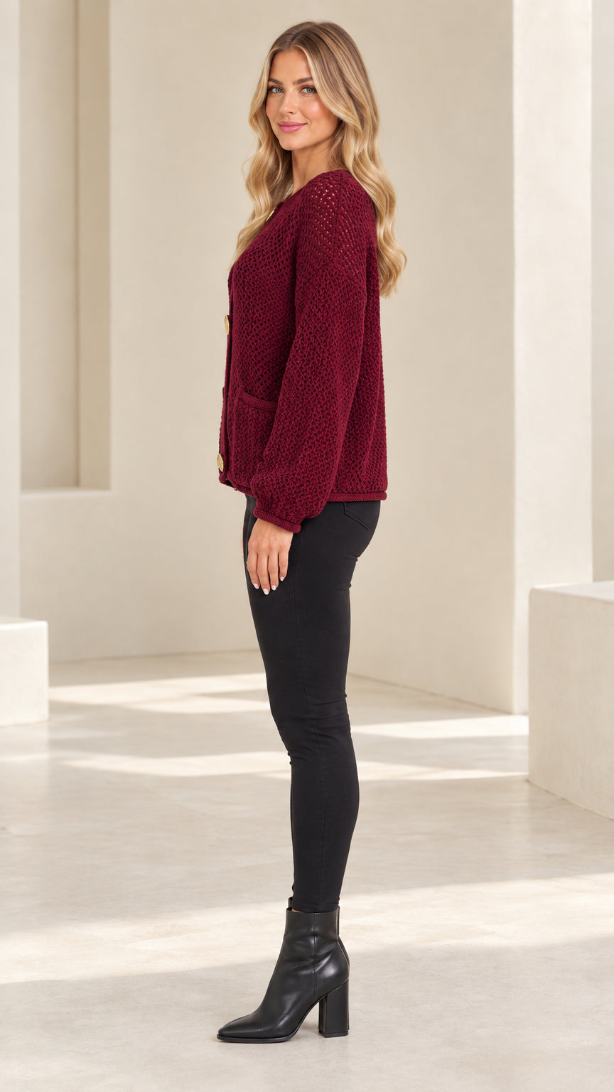 Side profile view of model wearing burgundy knit cardigan with balloon sleeves and black heeled boots