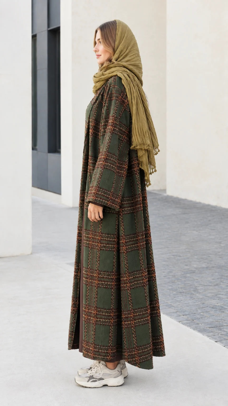 Side profile of woman wearing long olive green plaid cardigan coat