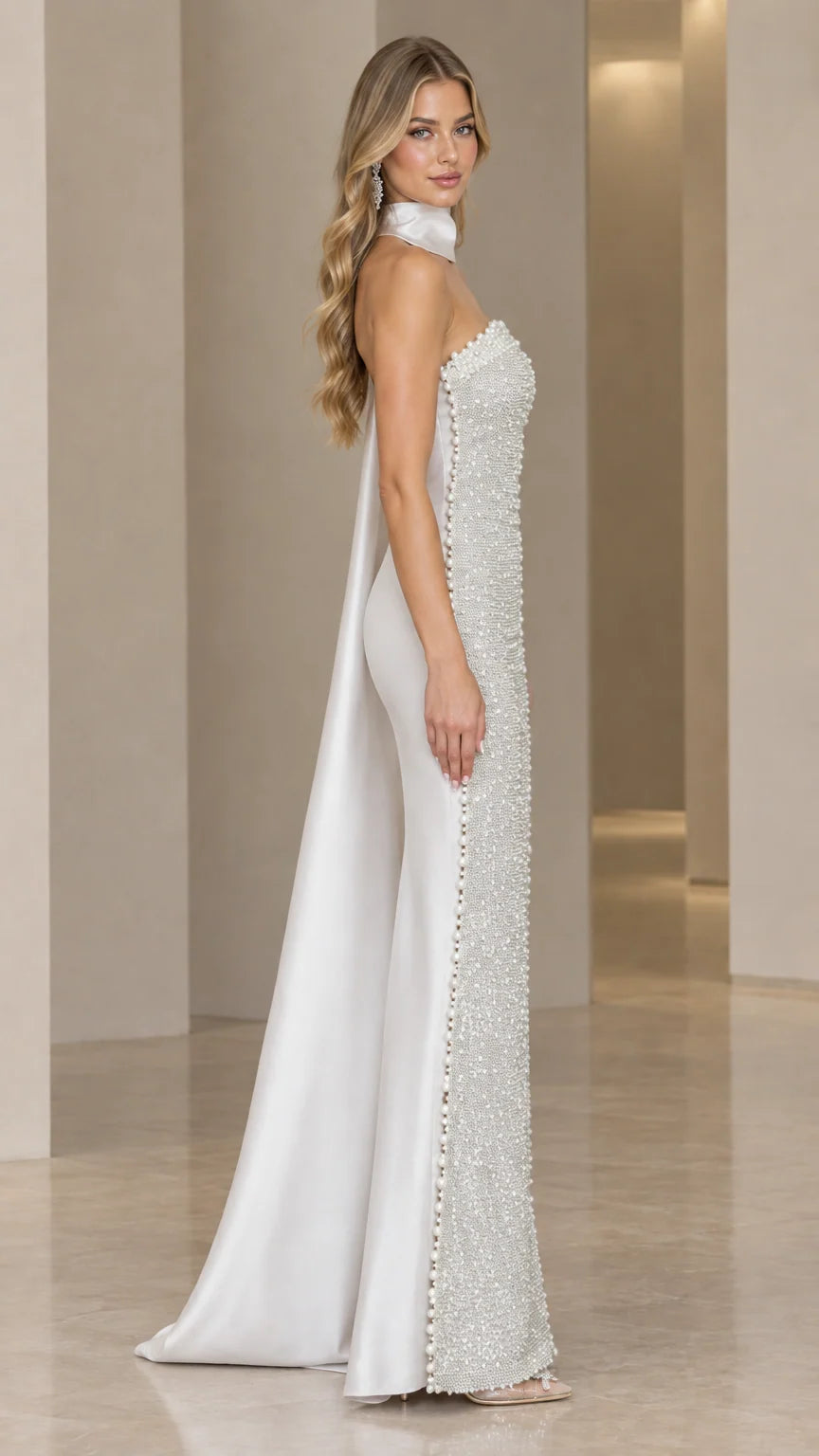 Side profile of silver beaded evening gown showcasing pearl trim and flowing cape