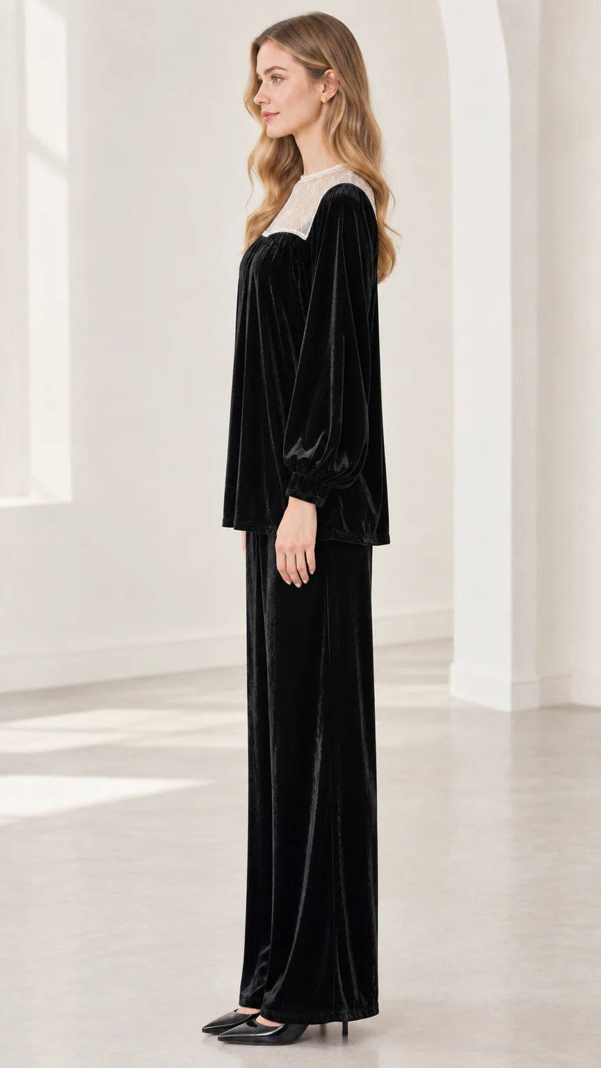 Side profile view of model in black velvet two-piece top and matching trousers