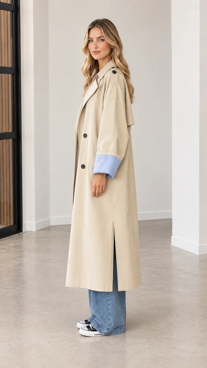 Side profile view of beige longline trench coat showing side split hem and relaxed fit