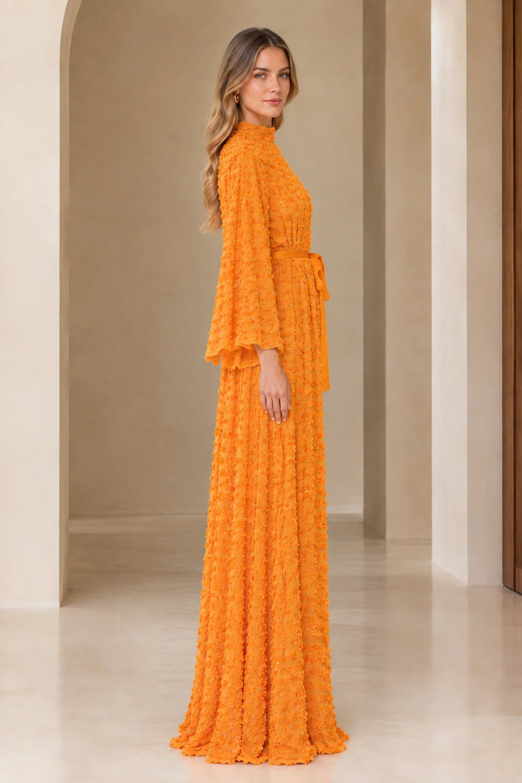 Side full view of orange textured sequin evening maxi gown with belt
