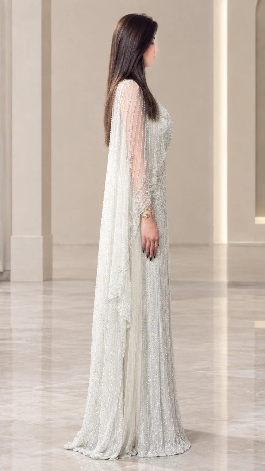 Side profile of woman wearing silver floor-length cape evening dress