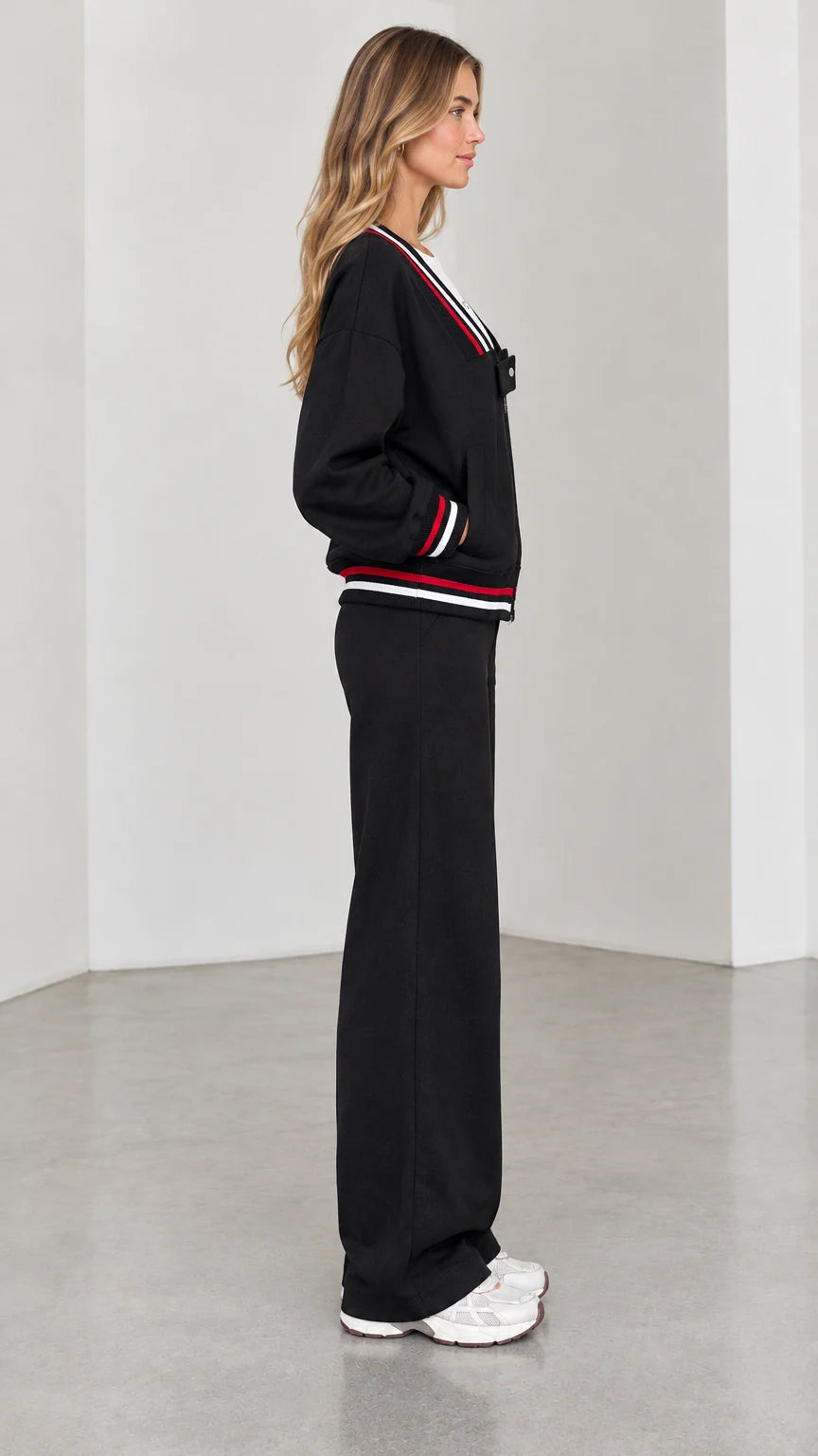 Side profile view of model in black two-piece wide leg tracksuit set