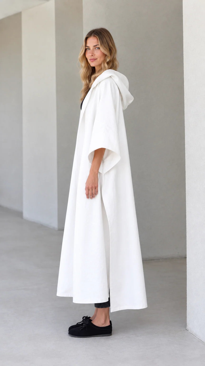 Side profile view of model wearing white hooded canvas cape duster