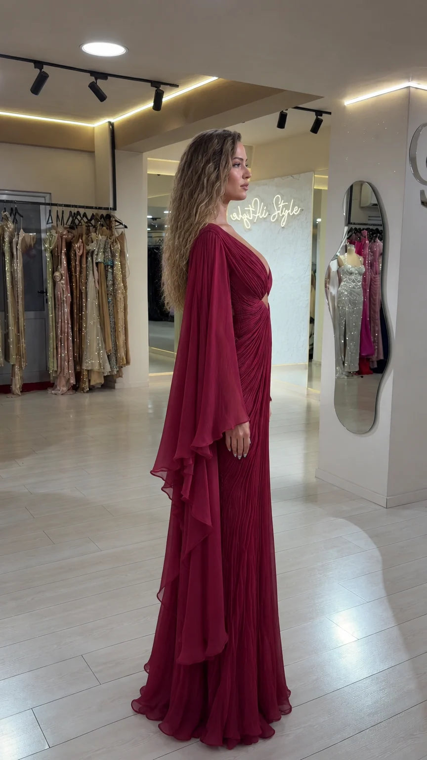Side profile view of burgundy pleated cape sleeve evening maxi dress