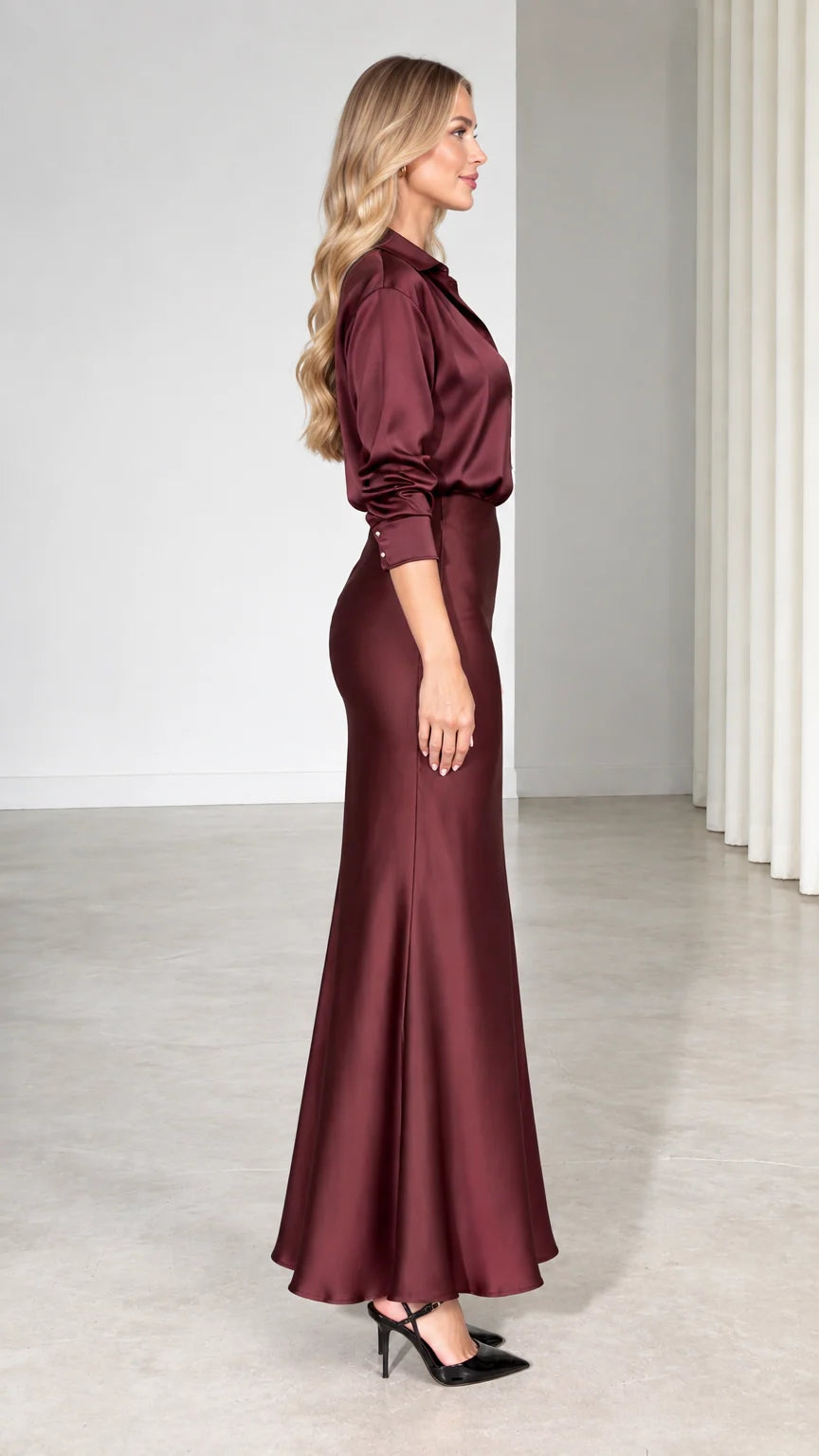 Side profile view of model in burgundy satin two-piece shirt and skirt outfit