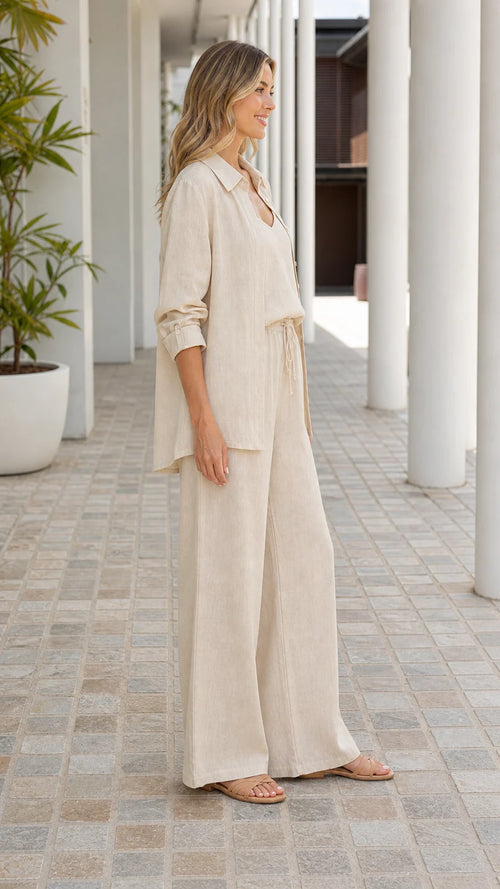 Side view of woman wearing beige linen button-down and trousers set