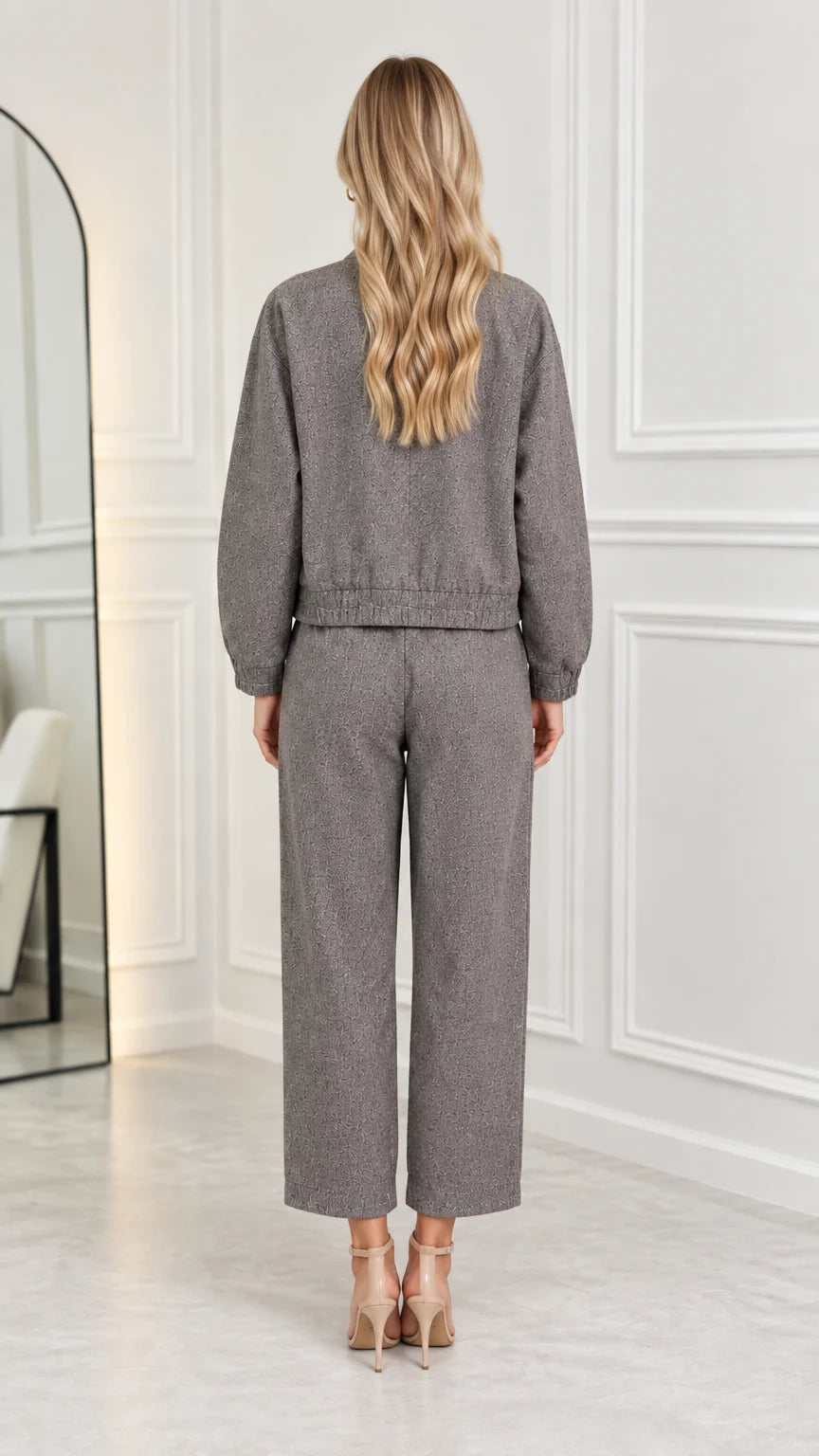Back view of model wearing grey two-piece bomber jacket and straight trousers set