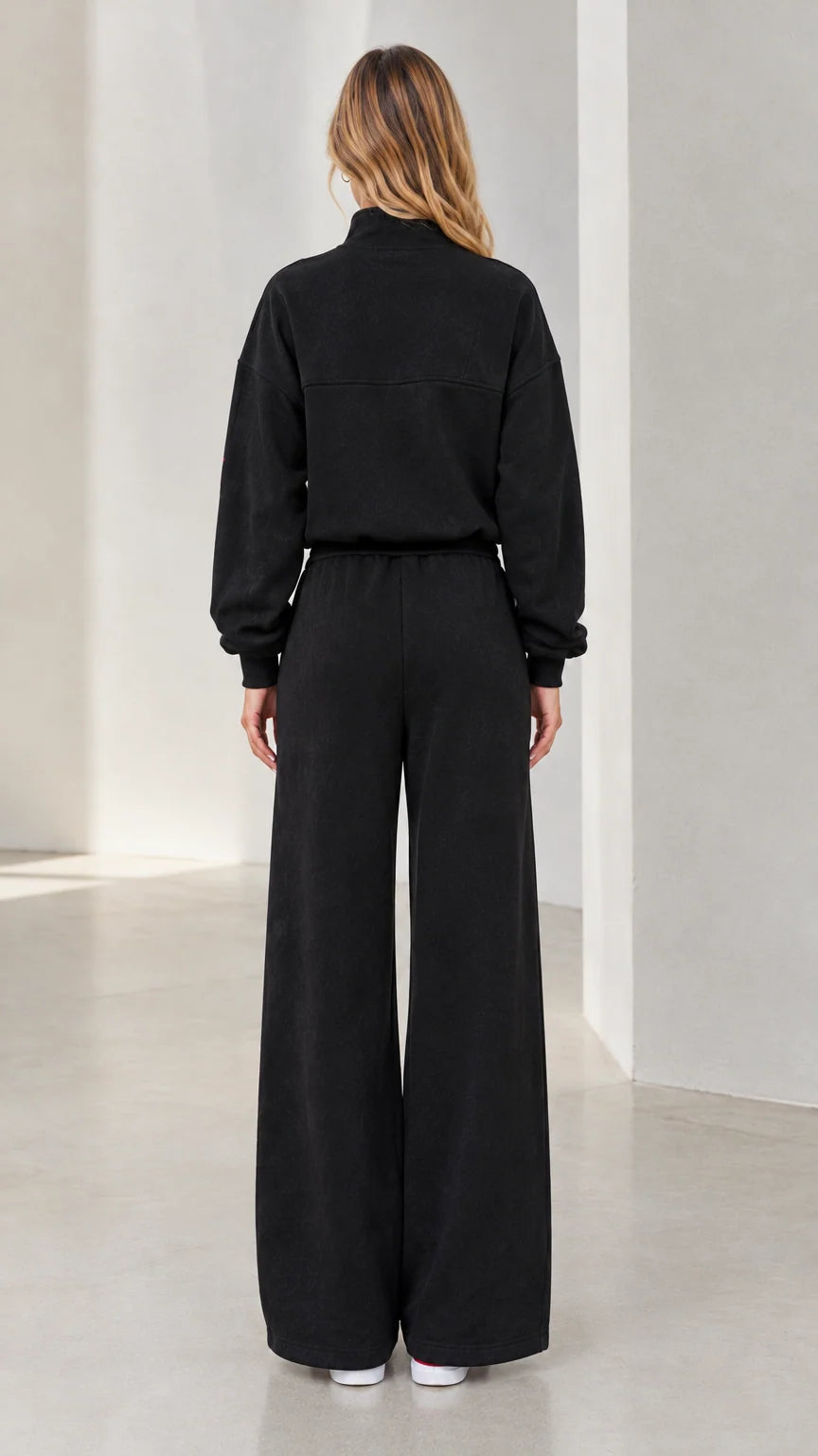 Back view of woman wearing black relaxed wide-leg sweatpants and half-zip top set