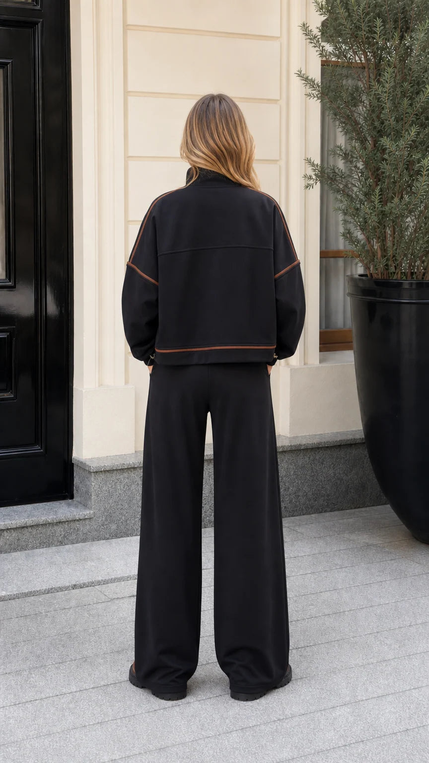 Back view of model showing contrast seam details on black zip jacket and wide-leg trousers