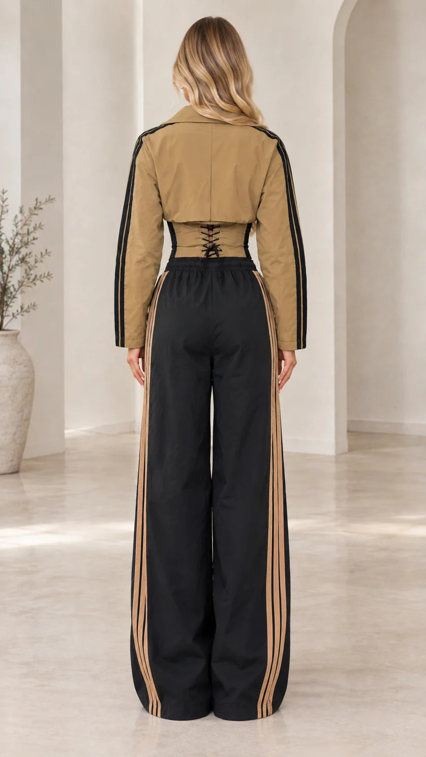 Back view of camel and black tracksuit jacket showing corset lace-up detail and wide pants