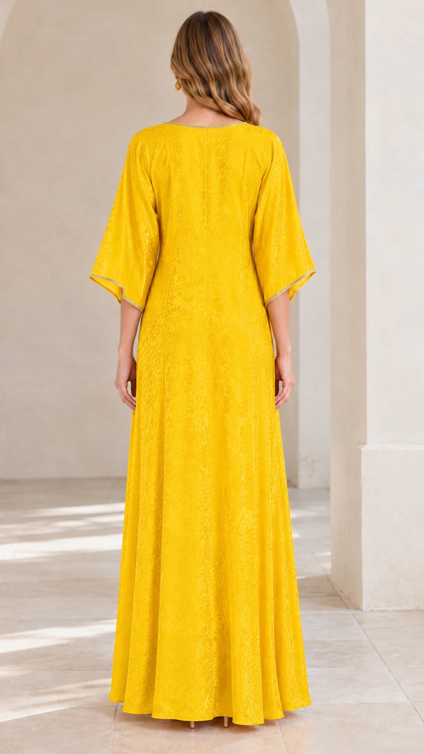 Back view of woman in flowing yellow jacquard kaftan maxi dress