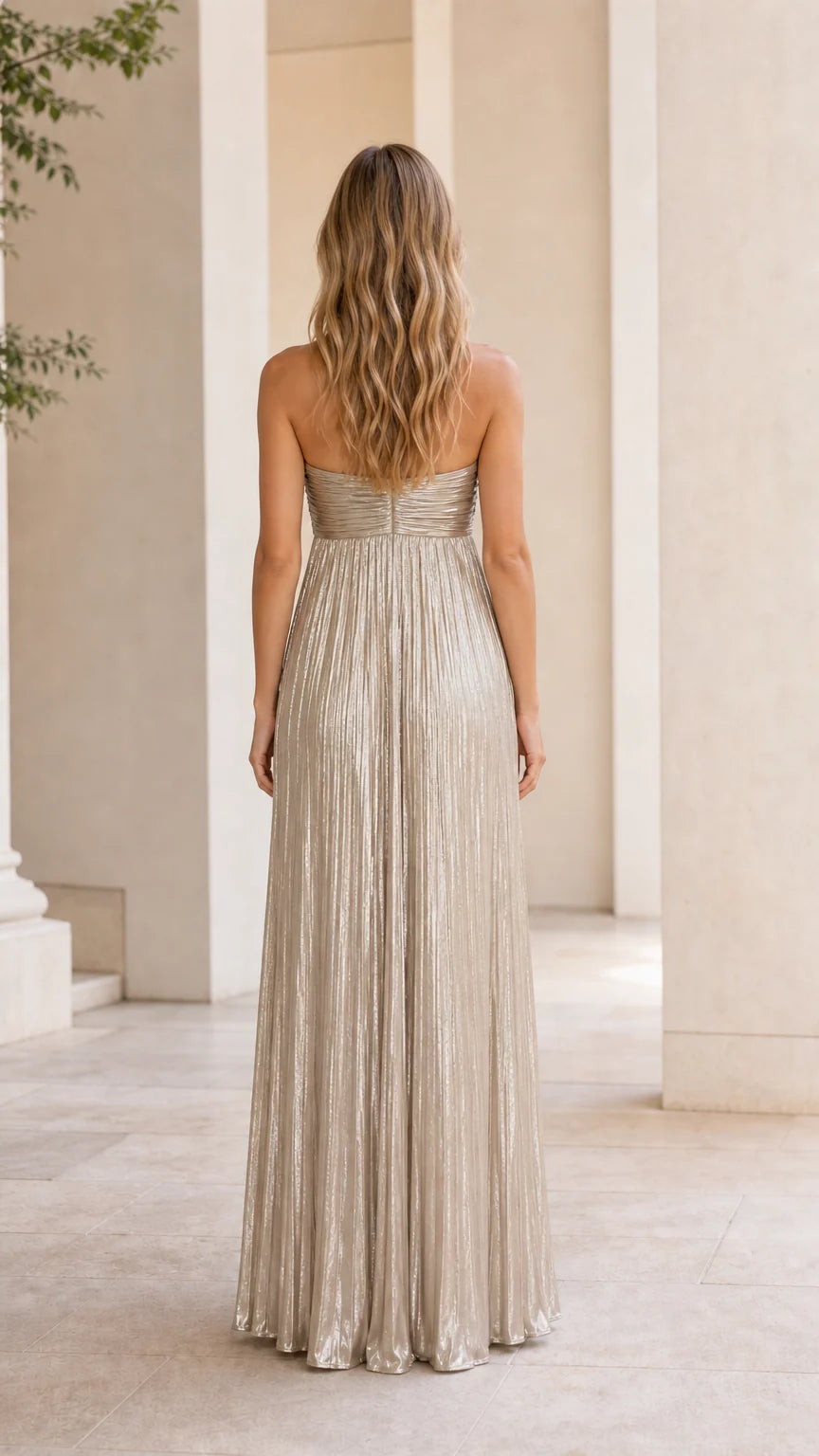 Back view of model wearing gold metallic pleated strapless maxi dress