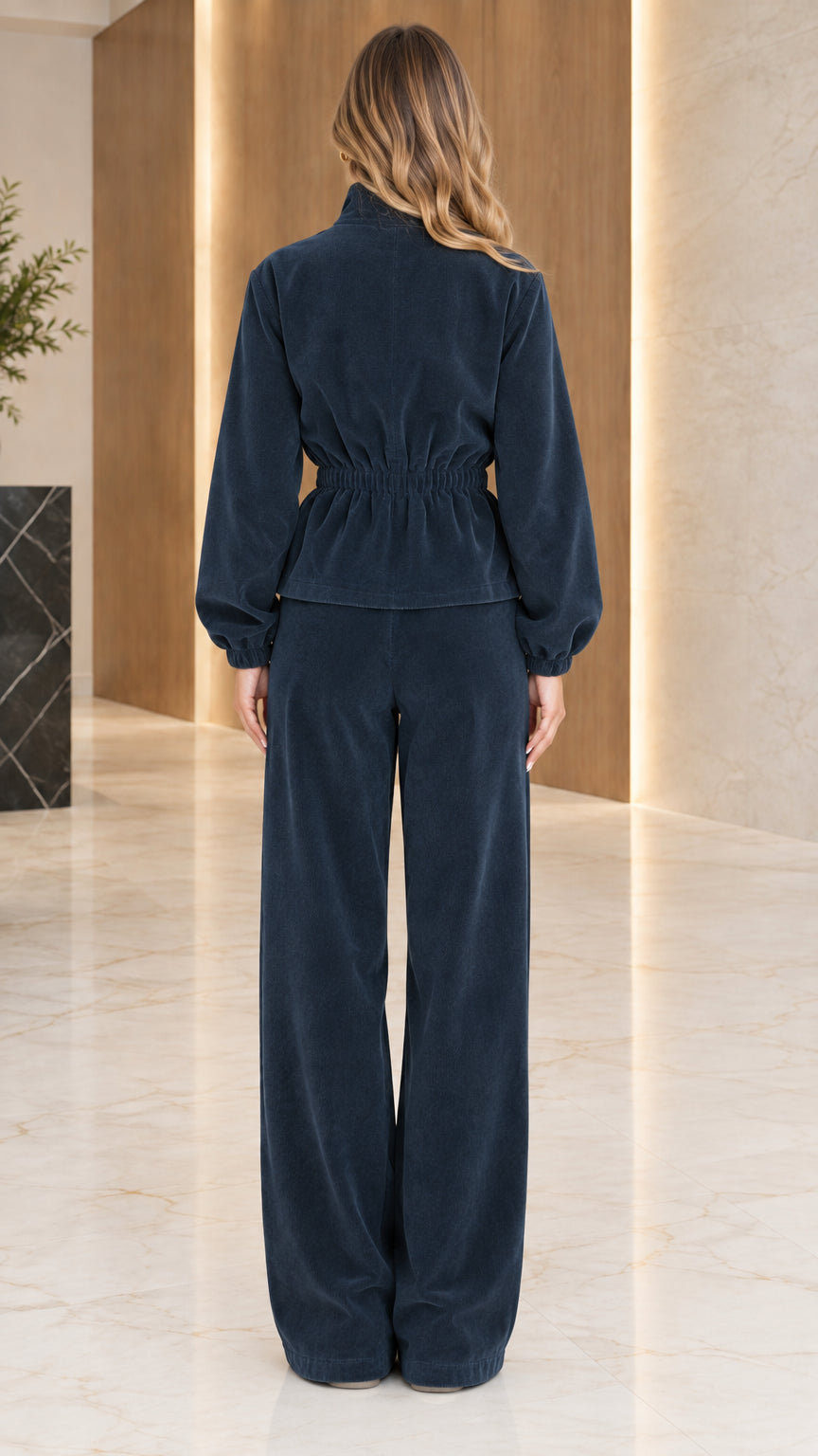 Back full-length view of woman wearing navy blue ribbed lounge set with cinched waist detailing