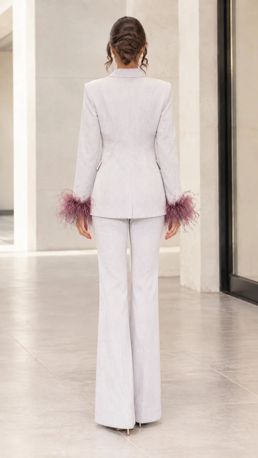 Back view of woman showing tailored silhouette of light grey blazer and flare pants