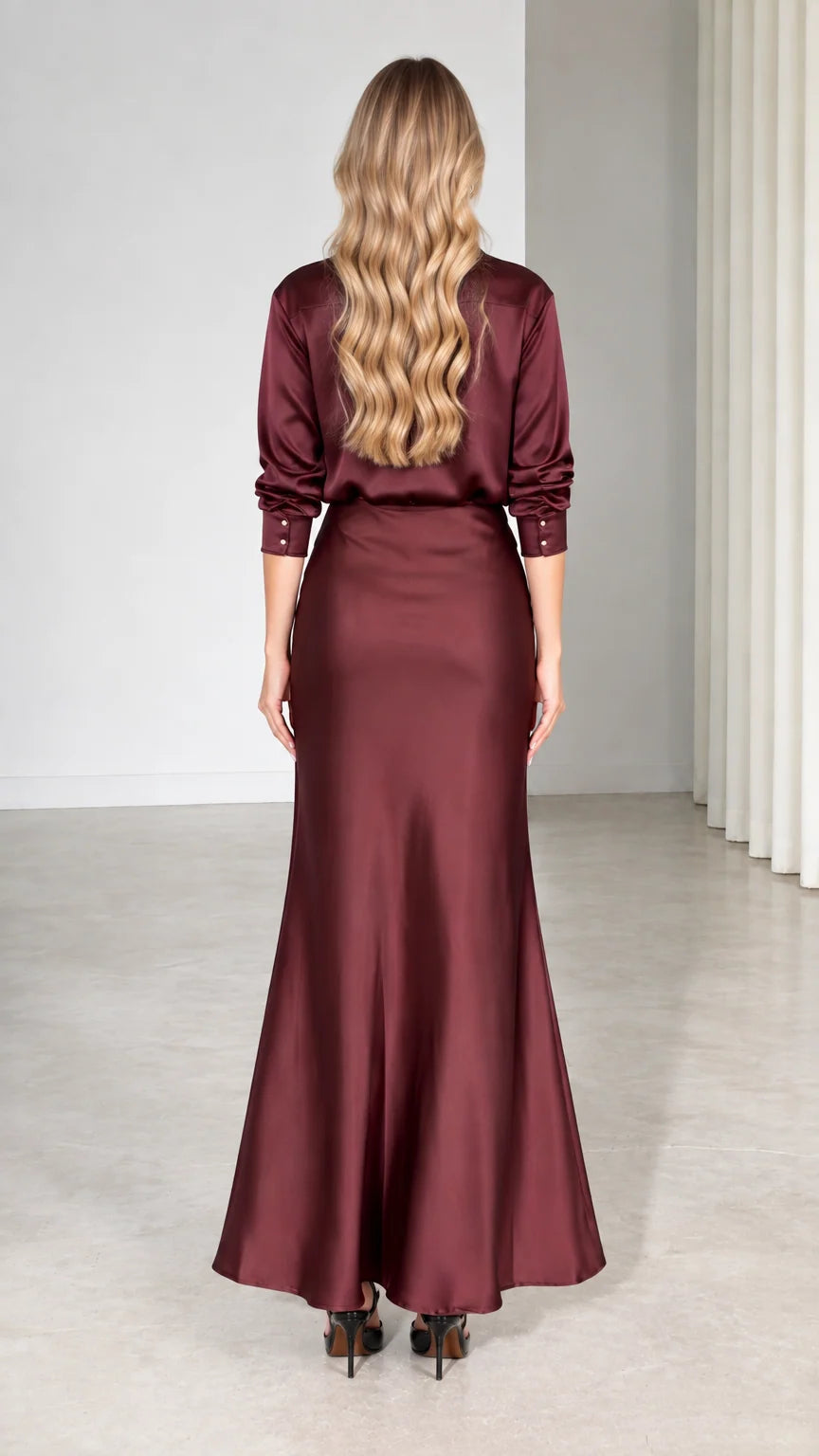 Back view of model showing burgundy satin long-sleeve shirt and maxi skirt