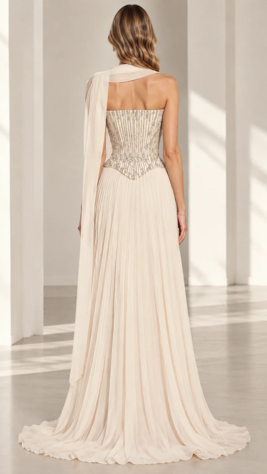 Back view of champagne strapless corset evening gown showing flowing pleated skirt and back sash