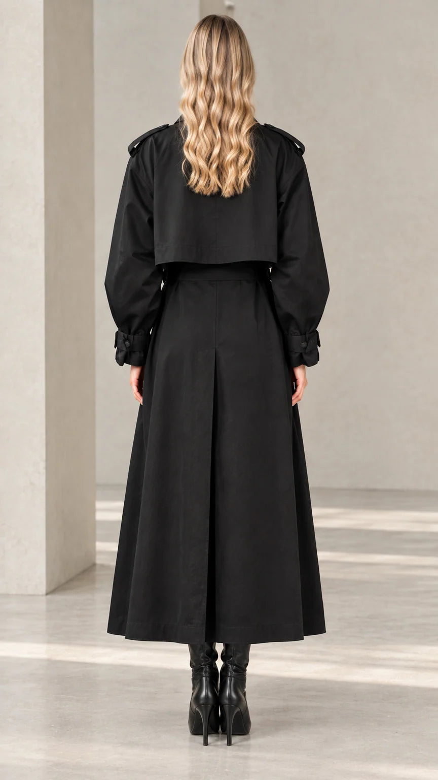 Back view of women's black maxi trench coat highlighting storm flap and inverted pleat