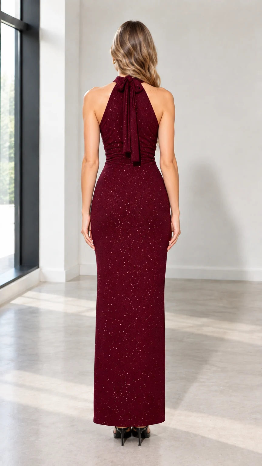 Back view of woman wearing burgundy halter maxi gown showing tie-back and hem slit
