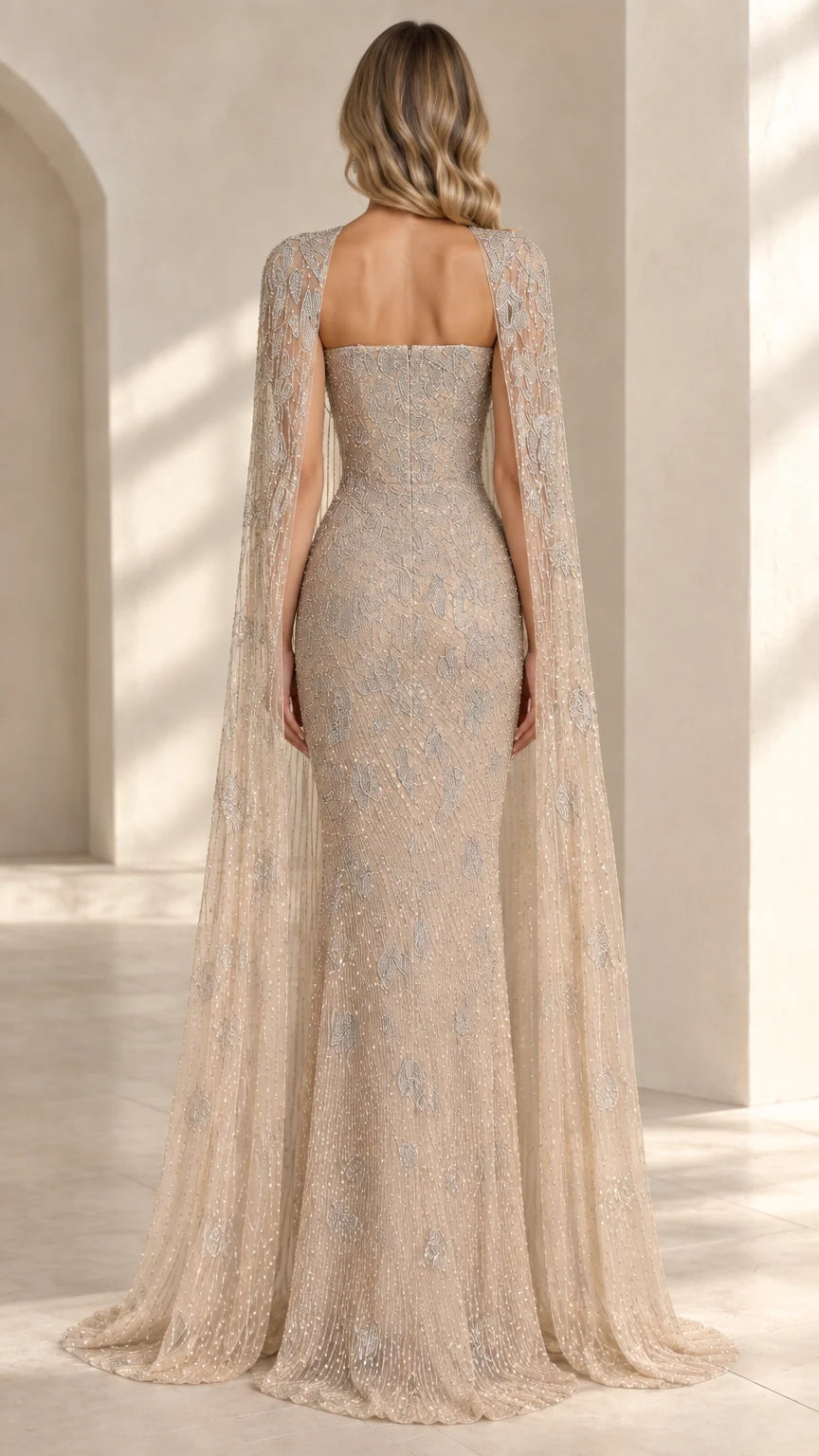 Back view of model wearing champagne strapless evening gown with long cape