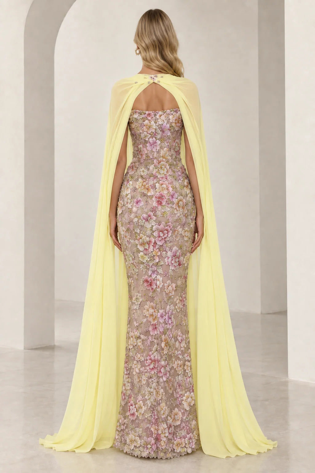 Back view of model showcasing full-length yellow chiffon cape and strapless embroidered dress