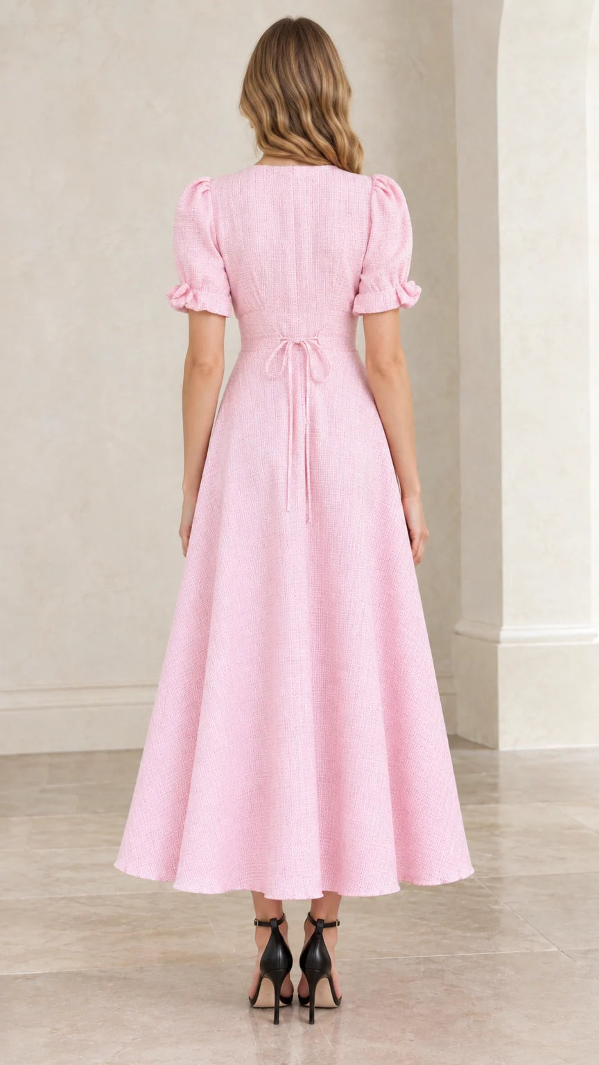 Back view of pastel pink textured dress highlighting tie back waist and zipper