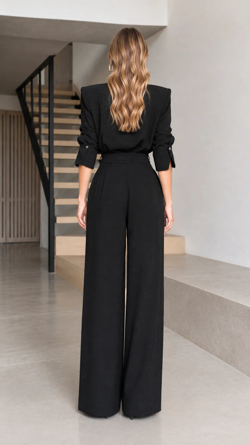 Back full view of woman wearing black structured-shoulder wide-leg jumpsuit