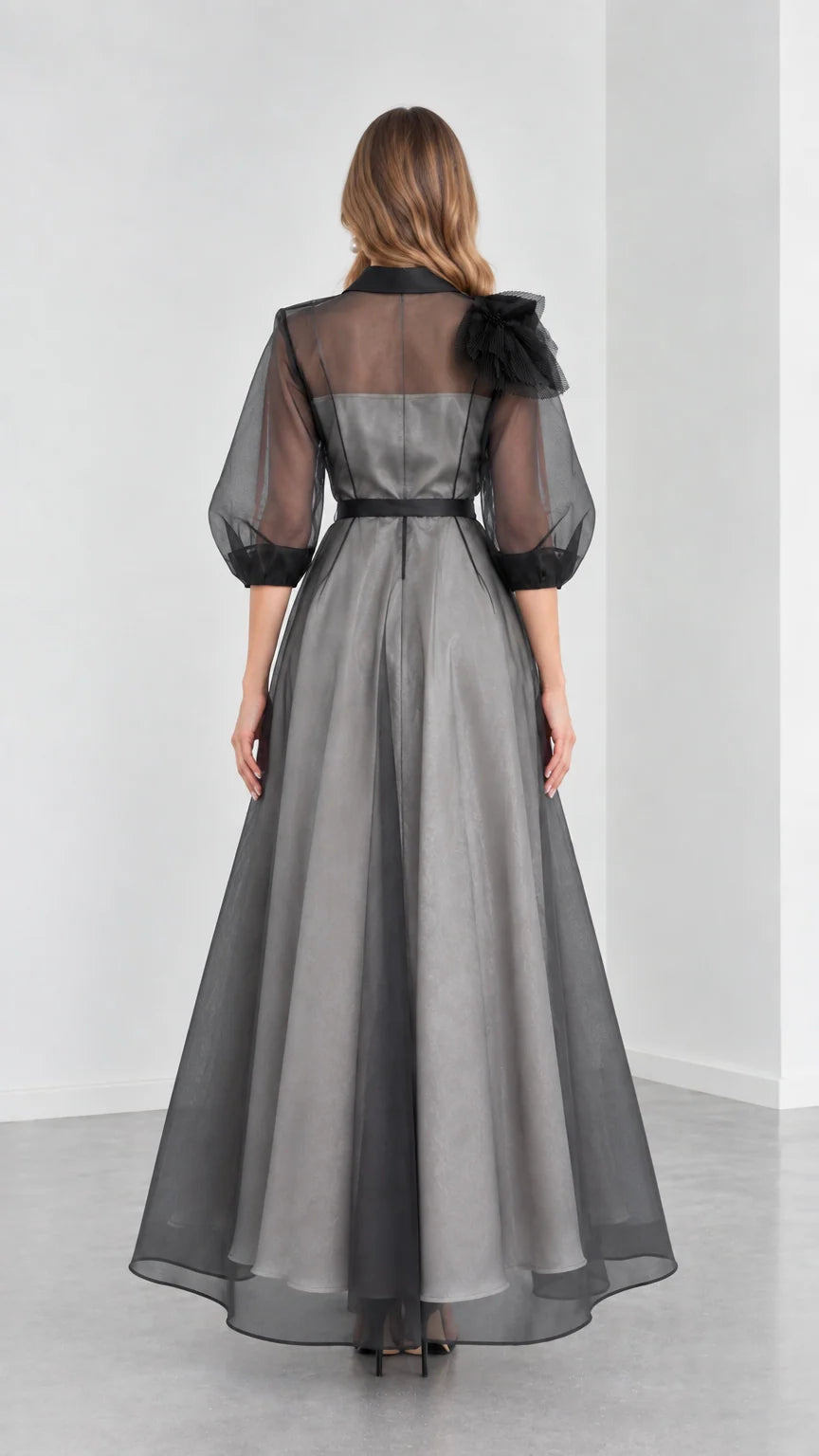 Back view of model showcasing the A-line drape and sheer upper back of Charcoal Grey gown