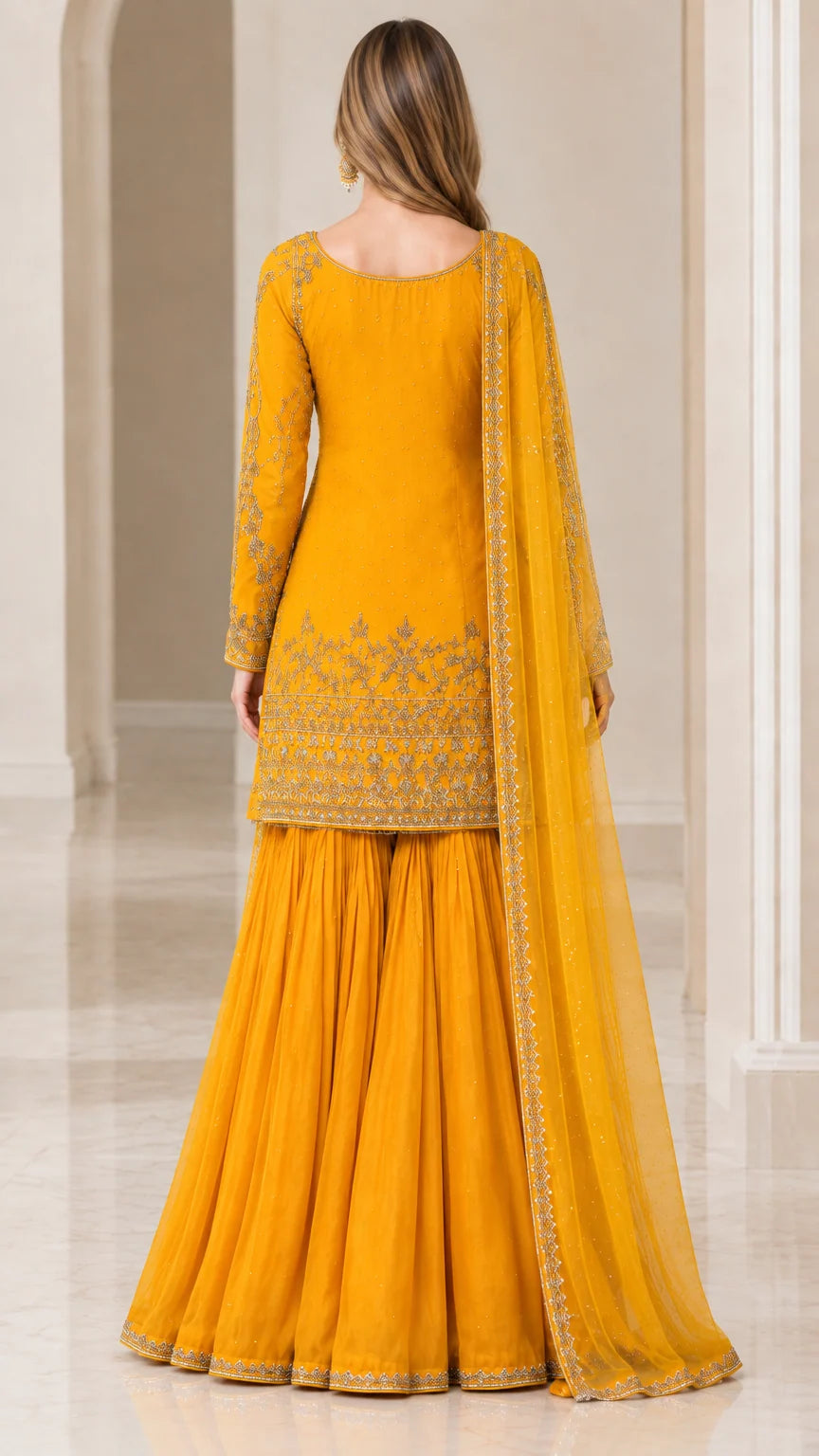 Back view of woman in Mustard Yellow embroidered sharara suit and sheer dupatta