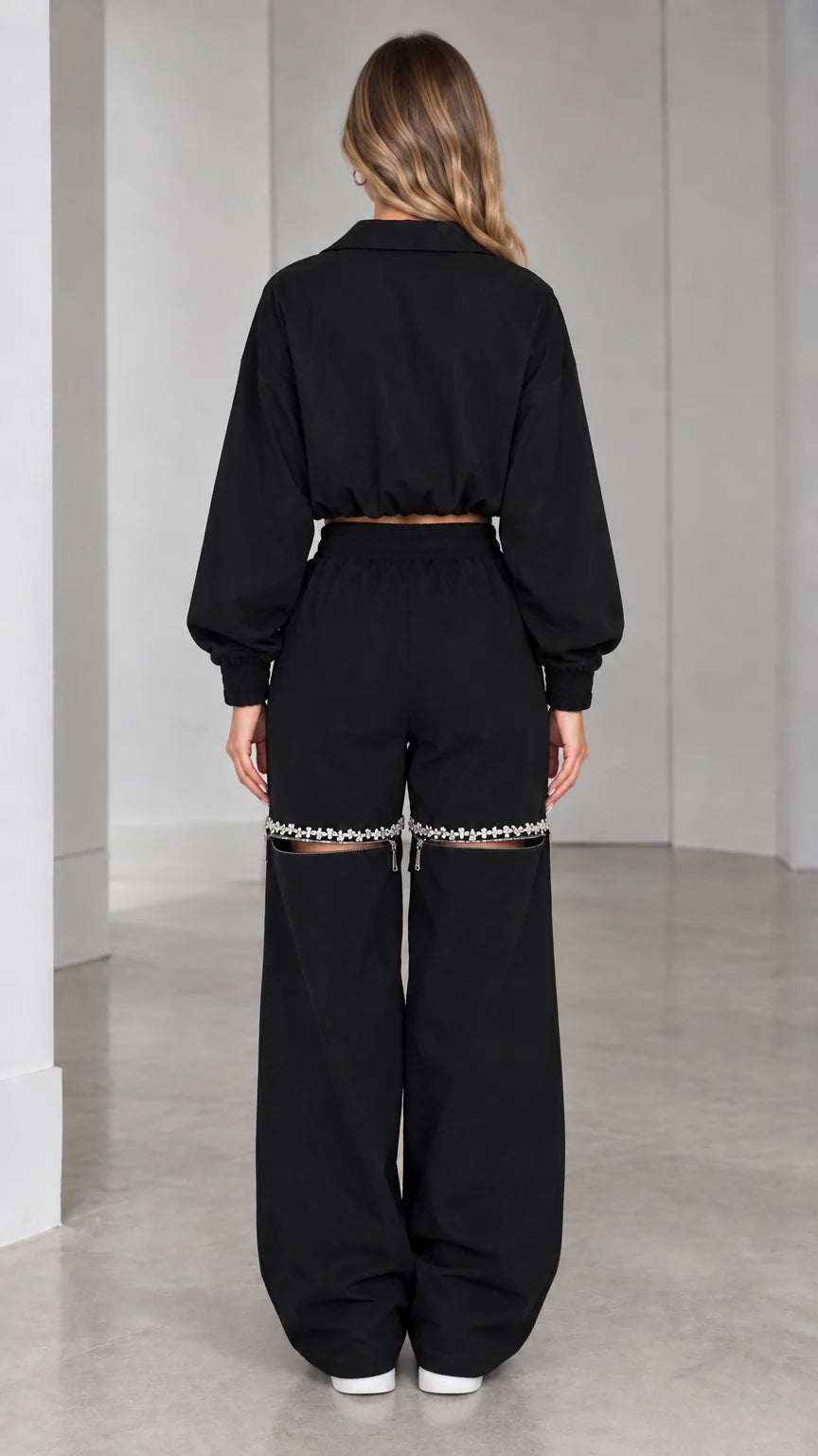 Back view of model wearing black cropped track jacket and wide-leg pants