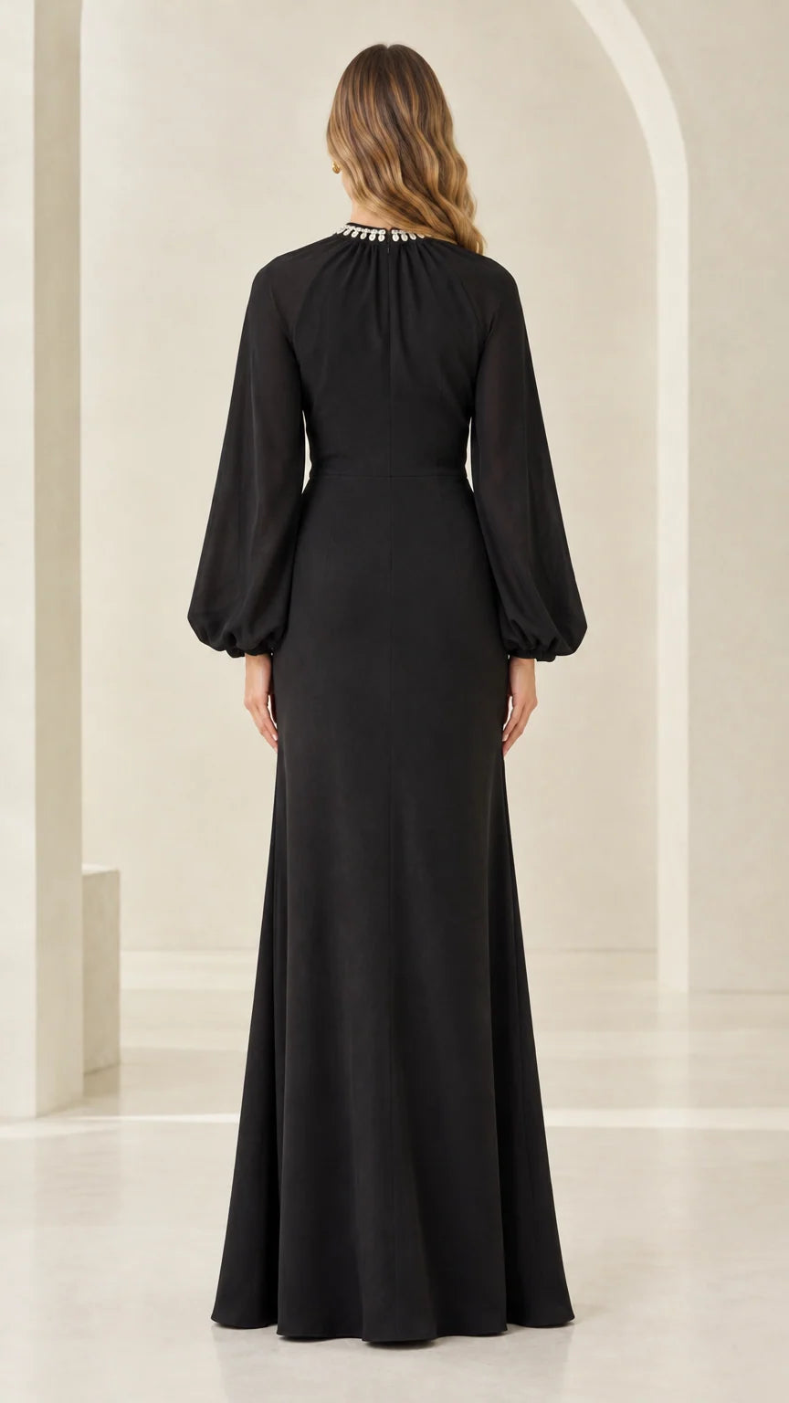 Back full-length view of woman in black cape sleeve evening maxi dress