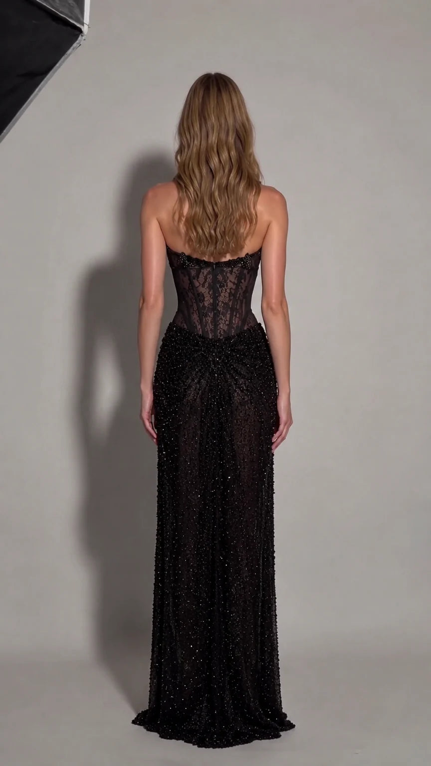 Back view of model showing open back and beaded maxi skirt of black formal gown