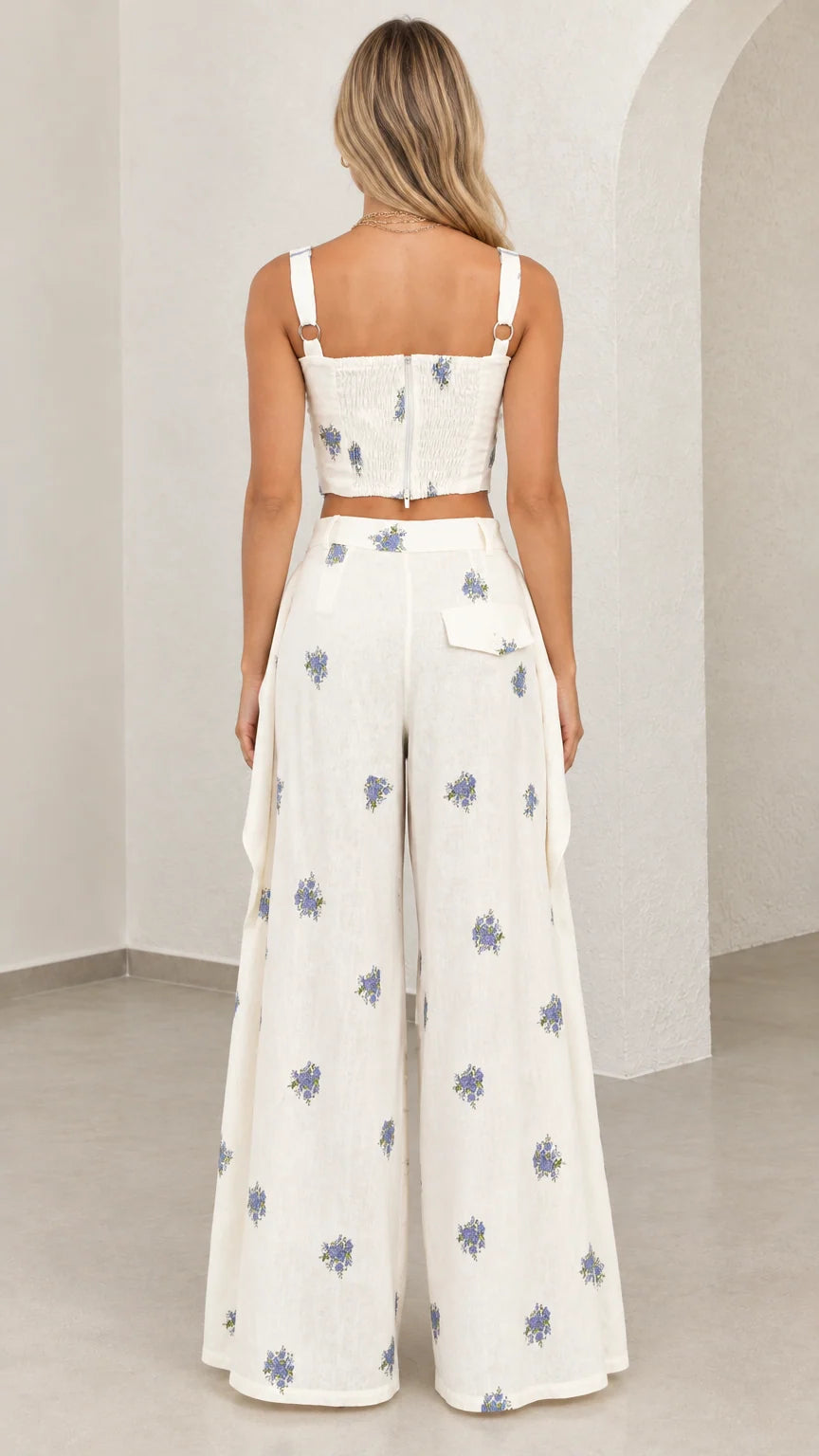 Back view of model wearing white floral embroidered bustier top and wide leg pants