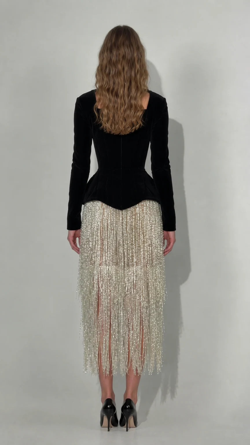 Back view of black long sleeve velvet corset dress with fringe midi skirt