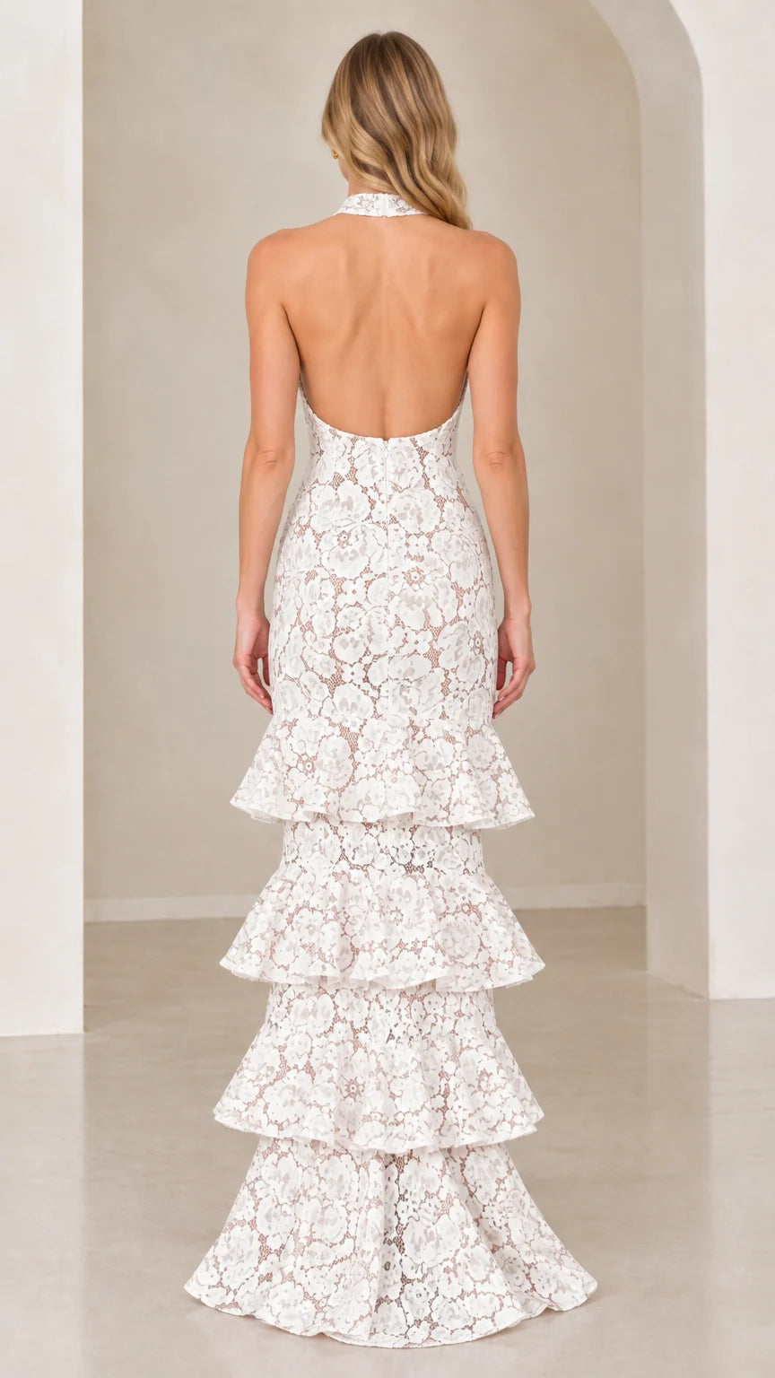 Back view of model showing open back design on White tiered lace evening gown