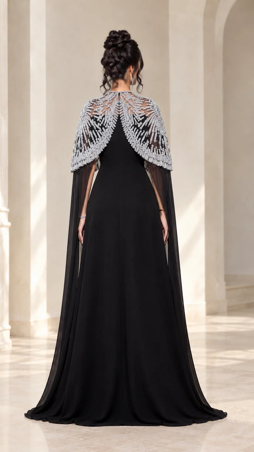 Back view of black evening gown featuring flowing sheer embellished cape