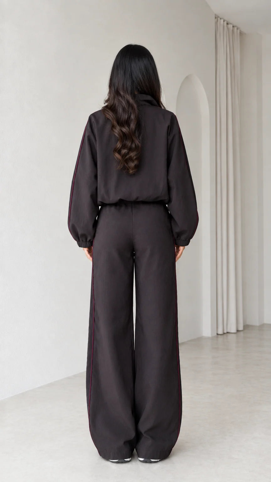 Back view of model in dark brown relaxed track jacket and wide leg pants